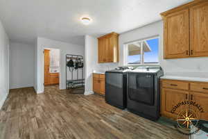 Laundry room featuring dark wood finished floors, cabinet space, washer and dryer, and baseboards