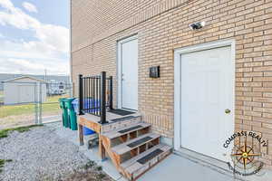 Garage man door and separate basement entrance to apartment. Property entrance featuring brick siding, fence, and a gate