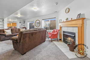 Living room featuring a textured ceiling, built in features, visible vents, and a tile fireplace