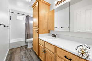 Full Bathroom with shower / bath combination with curtain, toilet, vanity, and wood finished floors