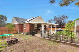 Back of property with an outdoor fire pit, a patio area, brick siding, a fenced backyard, and a shingled roof