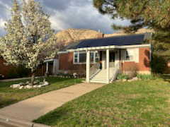 View of front of property featuring roof mounted solar panels, a front lawn, and a mountain view