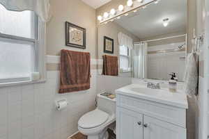 Bathroom featuring tile walls, plenty of natural light, vanity, toilet, and a shower with shower curtain