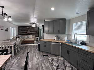 Kitchen with butcher block countertops, dishwasher, gray cabinetry, and a sink