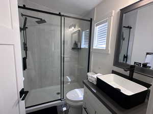 Full bathroom with vanity, toilet, a shower stall, and a textured ceiling