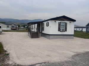 Manufactured / mobile home with a mountain view, a porch, cooling unit, and dirt driveway