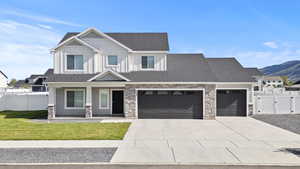 View of front of home with a garage, driveway, stone siding, covered porch, and board and batten siding