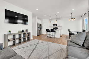 Living area with recessed lighting, baseboards, light wood-style floors, and an inviting chandelier