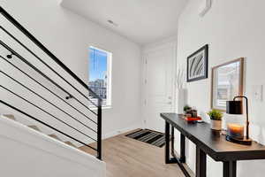 Foyer featuring light wood-type flooring, stairway, baseboards, and visible vents