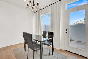 Dining room with a wealth of natural light, light wood-type flooring, baseboards, and a notable chandelier