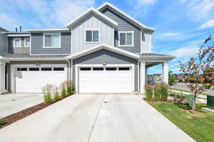 View of front facade with an attached garage, concrete driveway, and board and batten siding