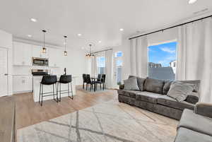 Living room featuring a chandelier, plenty of natural light, light wood-style flooring, and recessed lighting