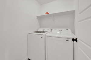 Clothes washing area with laundry area, washer and dryer, and baseboards