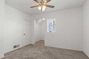 Carpeted main floor bedroom with a ceiling fan