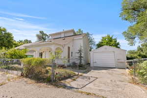 View of front of property featuring driveway, an outdoor structure, a fenced front yard, a garage, and stucco siding