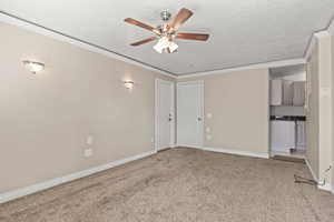 Unfurnished living room featuring a ceiling fan, light colored carpet, crown molding, and a textured ceiling