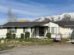 View of front of property with a mountain view, a shingled roof, and a fenced front yard