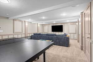 Game room with beamed ceiling, light carpet, recessed lighting, a decorative wall, and a textured ceiling