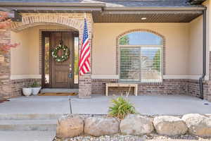 Entrance to property with brick siding, stucco siding, and a shingled roof