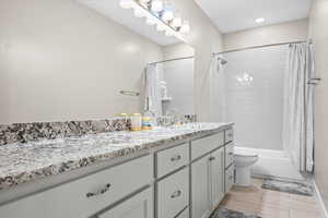 Bathroom featuring toilet, vanity, shower / tub combo, and wood tiled floor