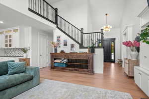 Living room with a towering ceiling, stairs, an inviting chandelier, and wood finished floors