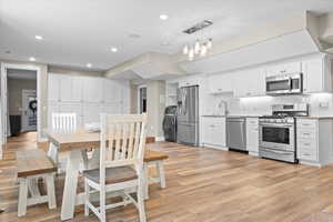 Dining room featuring washer / clothes dryer, light wood-style floors, recessed lighting, and baseboards