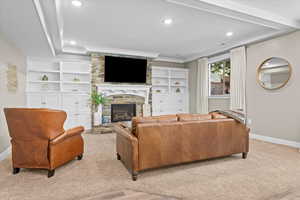 Living area with baseboards, a tray ceiling, a fireplace, crown molding, and carpet flooring