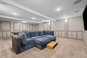 Living room with a decorative wall, light colored carpet, and a textured ceiling