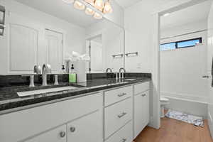 Full bath with double vanity, toilet, wood finished floors, and a sink