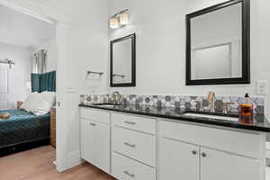 Bathroom with ensuite bath, wood finished floors, double vanity, and a sink