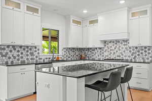 Kitchen featuring white cabinets, a center island, light wood-style floors, and a sink
