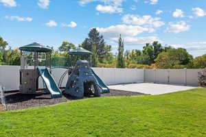 View of jungle gym with a patio, a lawn, and fence
