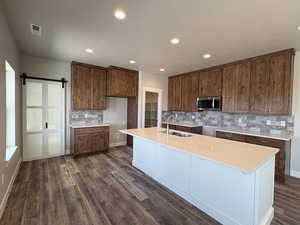 Kitchen featuring stainless steel microwave, a sink, decorative backsplash, dark wood finished floors, and recessed lighting