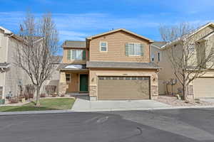 View of front of property with stone siding, concrete driveway, a garage, and a shingled roof