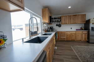 Kitchen with recessed lighting, a sink, dark wood-type flooring, light countertops, and stainless steel refrigerator with ice dispenser