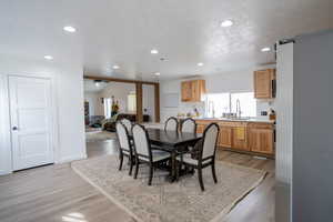 Dining area featuring light wood-style flooring, a textured ceiling, recessed lighting, baseboards, and ceiling fan