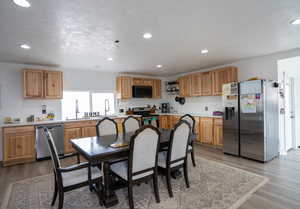 Kitchen with recessed lighting, light wood-type flooring, appliances with stainless steel finishes, and light countertops