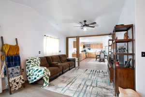 Living room with light wood-style flooring, lofted ceiling, and ceiling fan