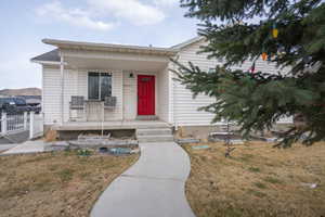 View of front facade with covered porch, a front yard, and fence