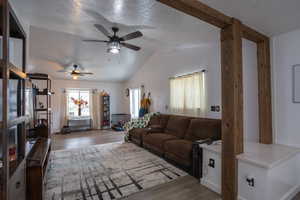 Living area with a textured ceiling, vaulted ceiling, wood finished floors, and ceiling fan