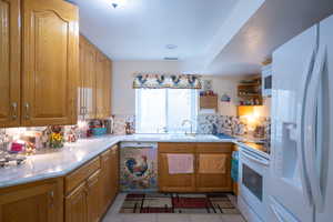 mother in law Kitchen with light tile patterned floors, backsplash, white appliances, and open shelves