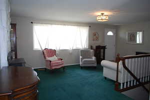 Sitting room with an upstairs landing, carpet, a chandelier, and baseboards