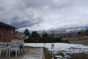 Snowy yard featuring outdoor dining space and a mountain view