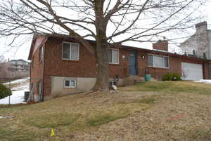 Single story home with brick siding, a chimney, a front yard, and fence