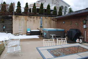 View of patio featuring fence, a grill, and a hot tub