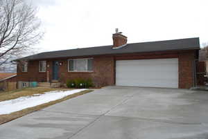 Single story home with fence, driveway, a chimney, a garage, and brick siding