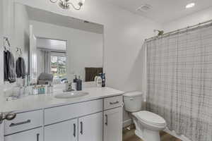 Ensuite bathroom featuring vanity, toilet, wood finished floors, and visible vents