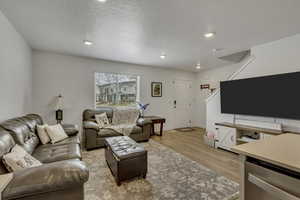 Living area featuring recessed lighting, baseboards, a textured ceiling, and light wood finished floors