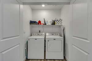 Washroom with light wood-style floors, washing machine and dryer, and laundry area