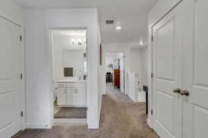 Corridor with a sink, recessed lighting, baseboards, and light carpet